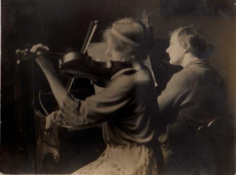 A photograph of Maisie and Evelyn Radford. Maisie is playing the violin and Evelyn is playing the piano.